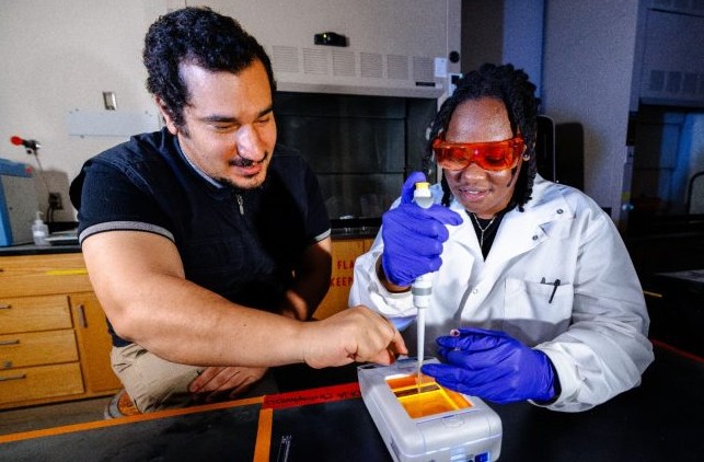 student working with professor in lab