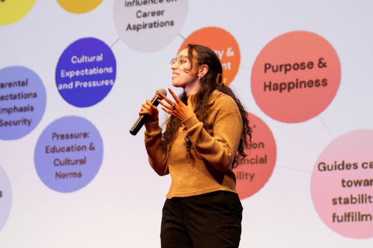 Laura Botros with microphone presenting